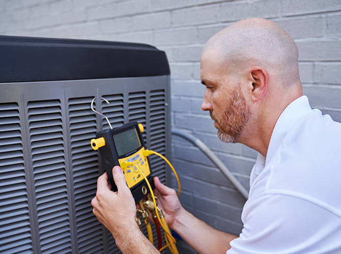 Service technical working on an air conditioner Service technical working on an air conditioner